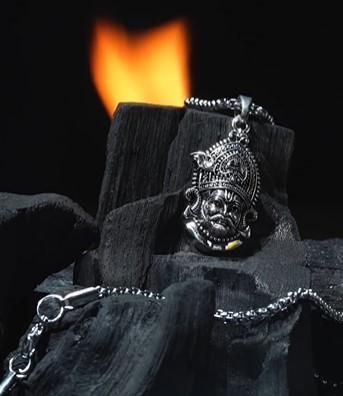 Shri Khatu Shyam Ji Maharaj Pendant with Chain resting on charcoal with a flame in the background.