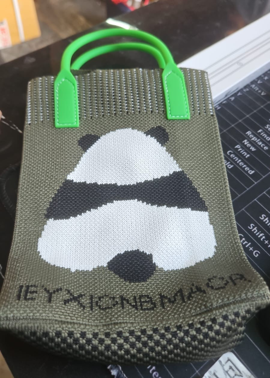 Close-up of panda graphic mini bag showing textured fabric and green top handles