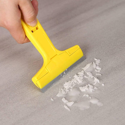 Scraper removing old sticker residue from wooden floor surface wide blade coverage effortless adhesive removal lifestyle photo